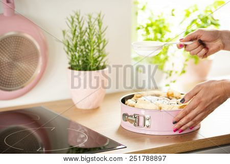 Woman's Hands Sifting Sugar On A Sponge Cake In A Pastel Pink Springform Pan In A Bright Kitchen Int
