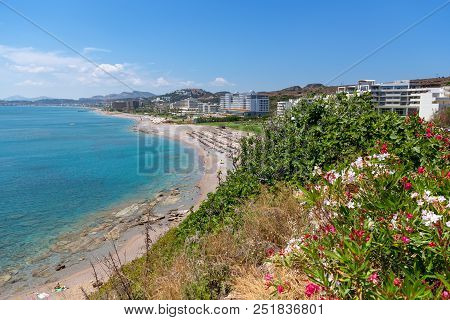View Of Sea Coast With Sandy Beach And Crustal Sea Water In Faliraki. Rhodes Island, Dodecanese, Gre