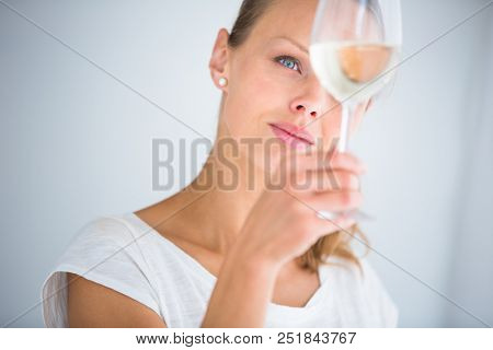 Gorgeous young woman with a glass of wine, smelling the lovely drink, savouring every sip (shallow DOF; color toned image)
