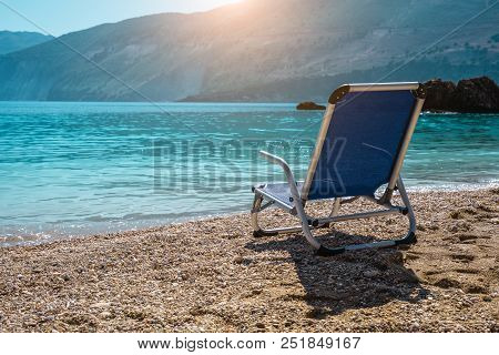 Beach Chair From Back On Tranquil Pebble Beach. Amazing View To Impressive Rocks In The Water. Seren