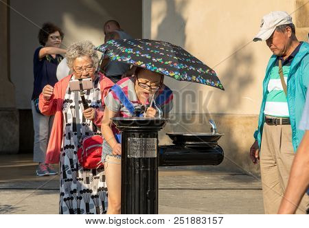 Cracow, Poland - July 5, 2018: Woman Is Refreshing At Fountain In Sweltering Hot Days On Main Square