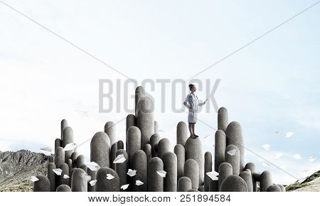 Young Female Doctor With Folder In Hands Satnding On Stone Column