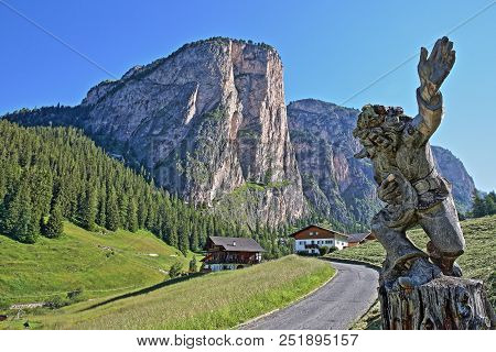 A Wooden Carving In Selva Near The Dantercepies Cable Car Station With Mount Stevia In The Backgroun