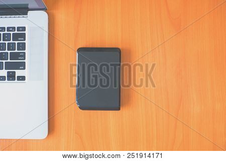 Portable External Hard Drive On The Desk Near The Laptop. External Hard With Laptop On Wooden Backgr
