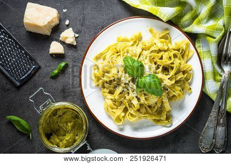 Tagliatelle Pasta With Pesto Sauce And Parmesan Cheese On Black Stone Table. Top View, Copy Space.