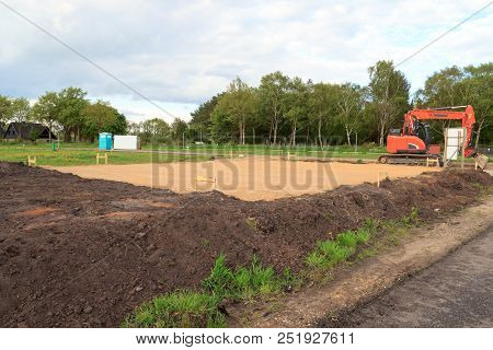 Construction Site For One Family House Filled With Sand And Digger In Building Area After Earthworks