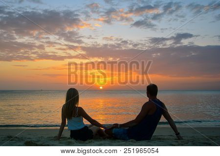 Couple Watching The Sunset On The Beach