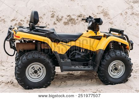 Side View Of Modern Yellow All-terrain Vehicle Standing In Desert On Cloudy Day