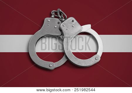 Latvia Flag  And Police Handcuffs. The Concept Of Observance Of The Law In The Country And Protectio