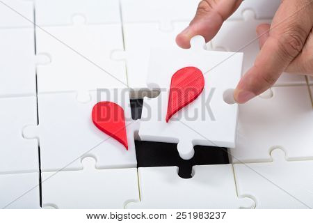 Man Connecting Broken Heart With Jigsaw Puzzle
