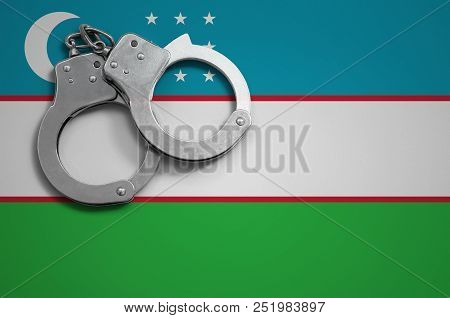 Uzbekistan Flag  And Police Handcuffs. The Concept Of Crime And Offenses In The Country