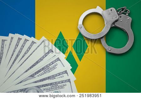 Saint Vincent And The Grenadines Flag  With Handcuffs And A Bundle Of Dollars. The Concept Of Illega