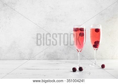 Kir Royal Champagne Cocktail On White, Copy Space. Flute Glasses With Berry Sparkling Champagne Drin