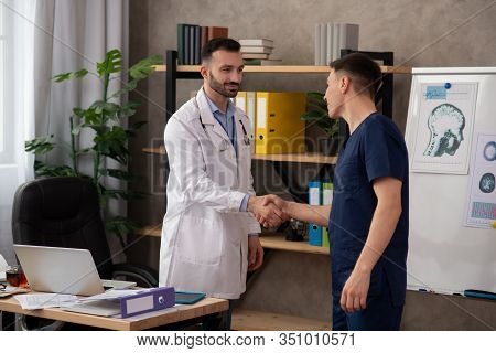 Two Young Doctors Shaking Hands In The Staffroom