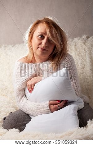 Adult Woman Hugs Her Favorite Pillow While Sitting On A Sofa.