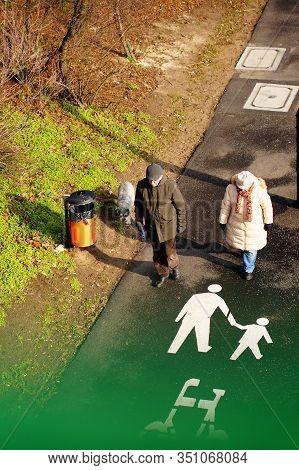 Poznan, Poland - February 15, 2020: Older Woman And Man Walking With Their Dog On A Sidewalk With Pe