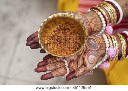 Indian Bride Hand Painted With Mehendi Or Myrtle Holding Brass Bowl Of Turmeric Paste
