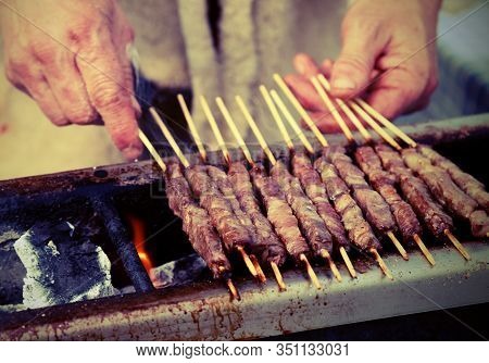 Elderly Man While Cooking Skewer Called Arrosticini In Italian Language With Old Toned Effect
