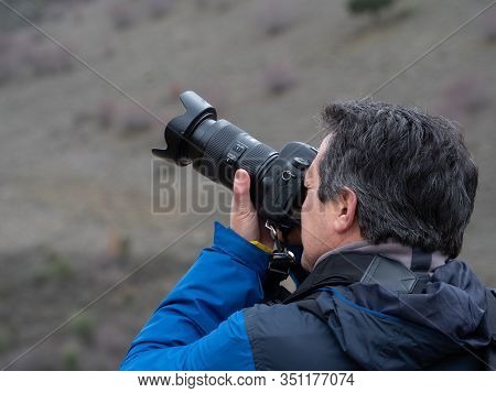 Man Taking A Photograph With A Reflex Camera And A Zoom Lens In The Middle Of The Mountain Maderuelo