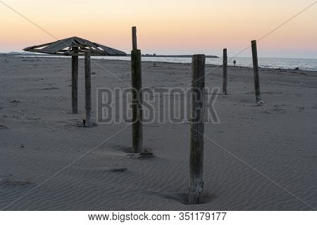Caspian Sea With Beach, Poles And  Wooden Beach Umbrella In The Evening.