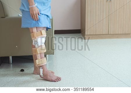 Patient Standing With Support Of Knee Brace And Plaster After Pcl Ligament Knee Surgery In Orthopedi
