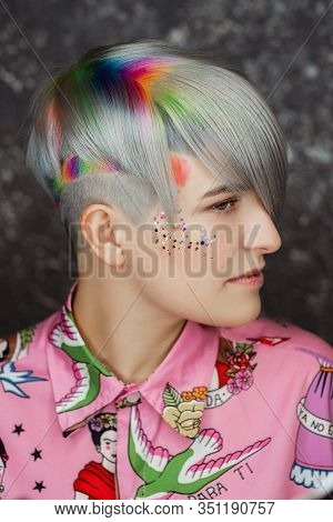 Portrait Of A Young Beautiful Girl In A Pink Shirt On A Gray Background With Dyed Hair. Short Haircu