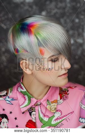 Portrait Of A Young Beautiful Girl In A Pink Shirt On A Gray Background With Dyed Hair. Short Haircu