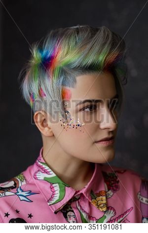 Portrait Of A Young Beautiful Girl In A Pink Shirt On A Gray Background With Dyed Hair. Short Haircu