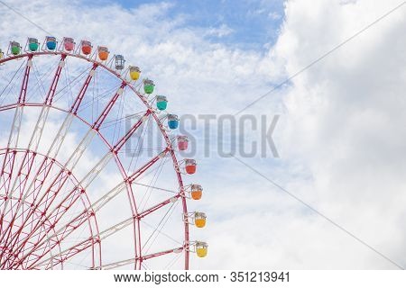 Photograph Of A Grtan Ferris Wheel Of Different Colors With A Blue Sky In The Background