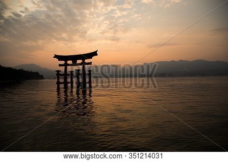 Photograph Of The Great Torii Of Miyajima Surrounded By Water At Sunset