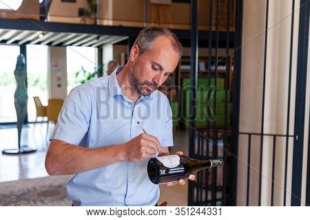 France Chablis 2019-06-21 Man Winemaker Signs Label Of Wine Bottle