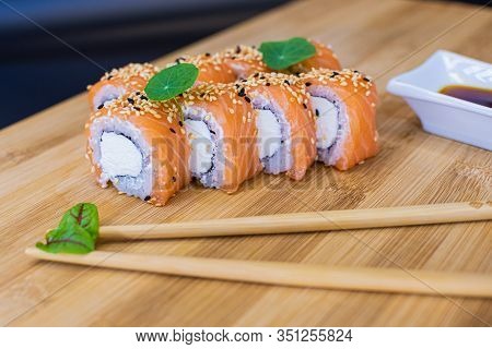 Japanese Sushi Food On A Wooden Board. Salmon, Rice, Wasabi, Ginger, Chopsticks Hashi Japanese Cuisi