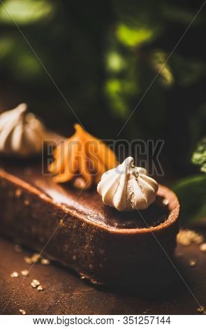 Belgian Chocolate, Swiss Merenge And Caramel Tart Over Rusty Background