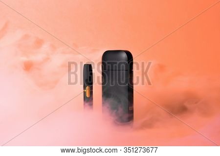 Iqos Electronic Cigarette In Smoke On An Orange Background.