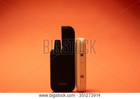 Black And White Iqos Electronic Cigarettes Isolated On Orange Background.