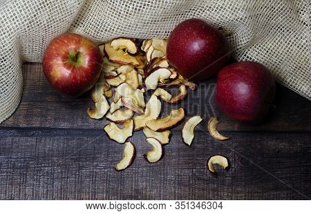 Dried Apple Chips And Three Red Apples On A Brown Wooden Table. Organic Natural Food. Close Up. Top 