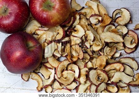 Dried Apple Chips And Three Red Apples On A White Wooden Table. Organic Natural Food. Top View. Clos