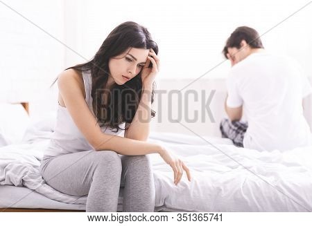 How Did We Get This. Sad Married Couple Sitting On Bed After Quarrel And Thinking About Relationship