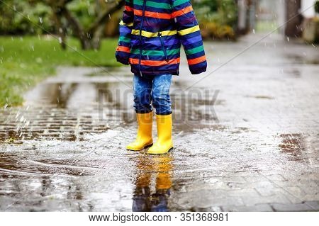 Close-up Of Kid Wearing Yellow Rain Boots And Walking During Sleet, Rain And Snow On Cold Day. Child