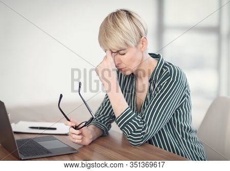 Eyestrain Concept. Middle-aged Lady At Laptop Having Headache And Eyes Fatigue Massaging Nosebridge 