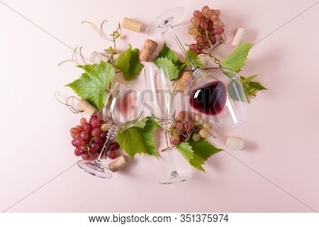 Assorted Wineglasses With Red, Rose And White Wine, Grape, Leaves And Cork Lying On Pink Background.