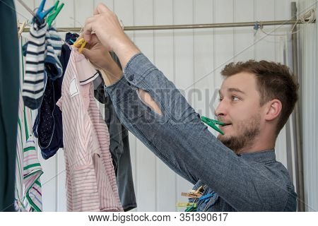 Portrait Of A Man About 30 Years Old With A Beard, Hangs His Clothes On A Clothesline, Leads A Bache
