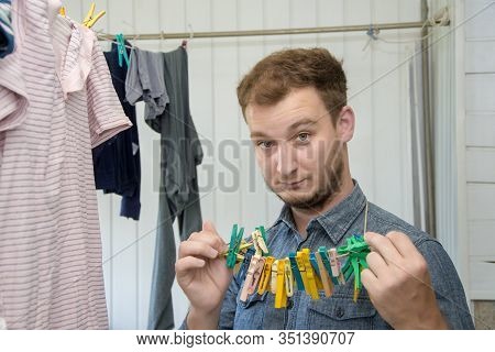 Portrait Of A Man About 30 Years Old With A Beard, Hangs His Clothes On A Clothesline, Leads A Bache