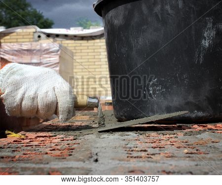 Bricklayers Hands With In Masonry Trowel Bricklaying New House Wall On Foundation. Close Up Of Indus