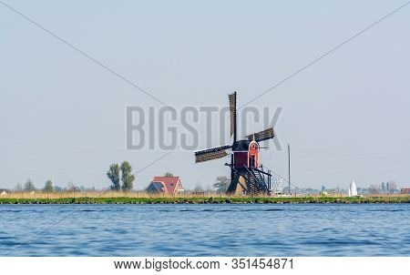 Dutch Landscape With Traditional Old Windmill On River And Green Pastures