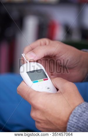 closeup of a caucasian man about to measure his blood glucose level by plalcing a strip in a glucose meter