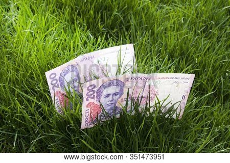 Ukrainian Money 200 Hrivnya On The Ground In Green Grass. Land Market Concept