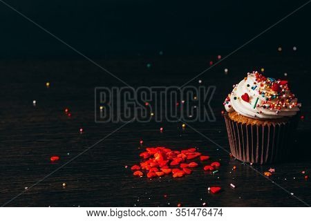 Cupcake Sprinkled With Decorations On A Black Background.
