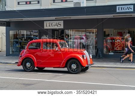 Napier - New Zealand - February 16 2020; Bright Red Morris 8 Car Passes And Is Reflected In Shop Win