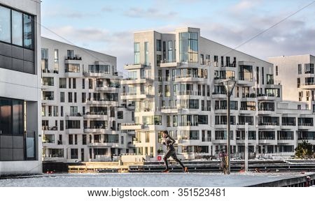 City run winter running man jogging through Copenhagen apartment buildings training cardio on city street. Active healthy lifestyle man runner outdoors in cold weather.